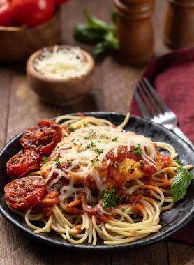 Makarnalı parmesanlı tavuk, sos ve fesleğen yapraklarıyla süslenmiş kızarmış domates ve akşam yemeği tabağında doğranmış maydanoz.