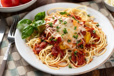 Makarna ve fesleğen yapraklarıyla süslenmiş soslu parmesanlı tavuk ve akşam yemeği tabağında maydanoz.