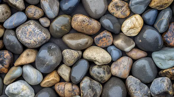 Assorted smooth river stones in various shades of gray, blue, brown, and beige, creating a natural, textured pattern.