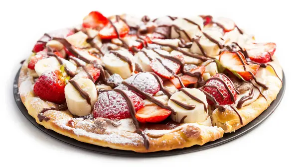 stock image A dessert pizza topped with fresh strawberries, banana slices, chocolate drizzle, and powdered sugar, presented on a white background.