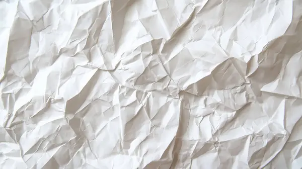 stock image A crumpled sheet of plain white paper, with textured folds and creases, highlighting its simplicity and rawness.