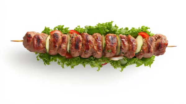 stock image A skewer of grilled kebabs with vegetables, served on a bed of lettuce, against a white background.