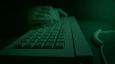 1980 'lerin klasik bilgisayar klavyesinde karanlık bir odada hackerlık yapan biri. Klavye ve hackerların elleri bilgisayar monitörünün yeşil parıltısıyla aydınlanır..