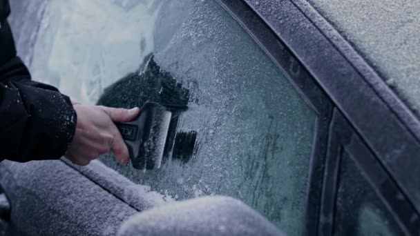 冬のコートの男は 氷柱を使用して 氷柱を使用して 氷柱の上の冷凍車の窓やフロントガラスから重い霜や氷を除去する冬の朝 — ストック動画