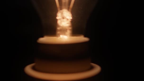 黒い背景から見た輝くタングステン電球フィラメントのクローズショット — ストック動画