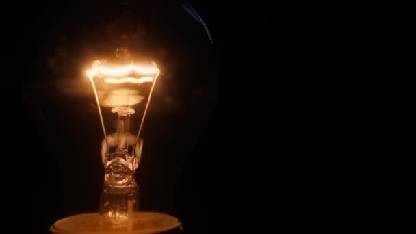 黒い背景から見た輝くタングステン電球フィラメントのクローズショット — ストック動画