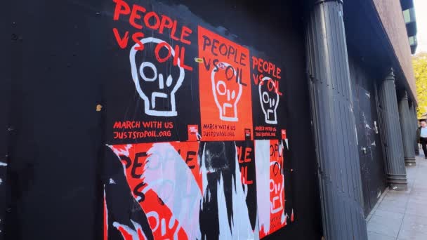 Norwich, Norfolk, United Kingdom - November 3, 2023. Fly-posted bright orange People vs Oil posters promoting the direct action protest group Just Stop Oil cover the painted hoarding of an empty shop unit in the centre of the city.