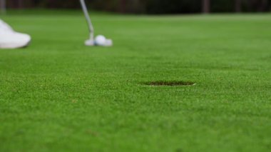 Golfçü Golf Topu Koyuyor ama Deliği Kaçırıyor. Golf sahasının zemin seviyesine çok yakın bir atış yapan golfçü golf topunu atıyor ama deliği ıskalıyor..