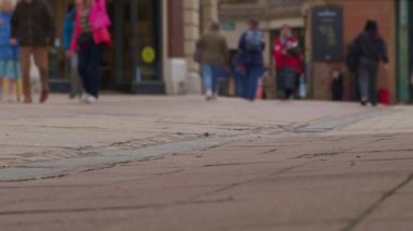 Bokeh 'te yayalar ve müşterilerle dolu şehir merkezi caddesi. İngiltere 'de şehir dolandırıcılığının ve ticari perakende faaliyetlerinin spesifik olmayan temsili. Şehir koşuşturması ve ticari faaliyet için spesifik olmayan temsiller gerektiren projeler için ideal.