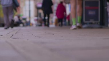 Bokeh 'te yayalar ve müşterilerle dolu şehir merkezi caddesi. İngiltere 'de şehir dolandırıcılığının ve ticari perakende faaliyetlerinin spesifik olmayan temsili. Şehir koşuşturması ve ticari faaliyet için spesifik olmayan temsiller gerektiren projeler için ideal.