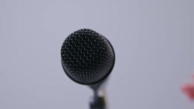 Siyah sahne vokalistlerinin mikrofonunu beyaz arka planda, yakın planda tutarken..