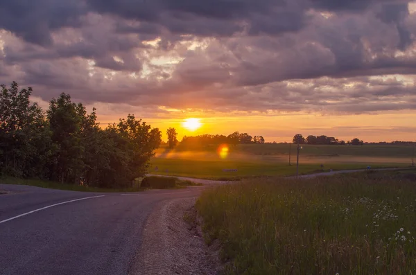 stock image sunset in a village in Latvia road field clouds sun beautiful sunset 2