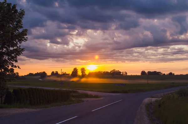 stock image sunset in a village in Latvia road field clouds sun beautiful sunset