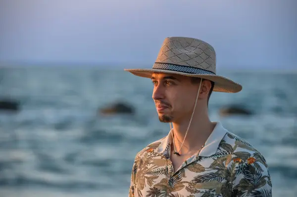 a young guy with a mustache and a hat  on a stone on the shore of the Mediterranean Sea 3