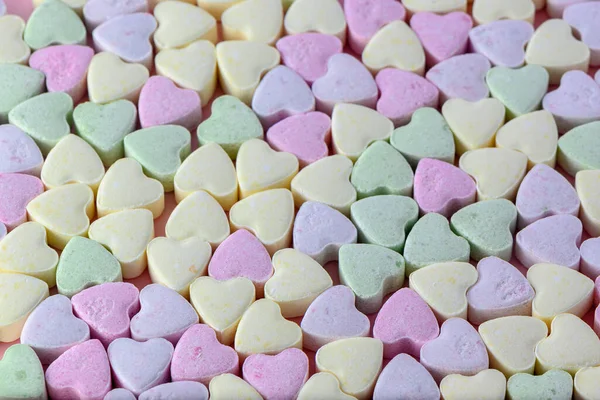 small heart-shaped candies on a pink background