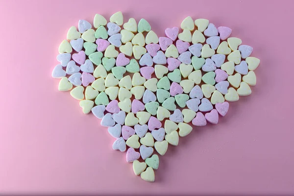 small heart-shaped candies on a pink background 1