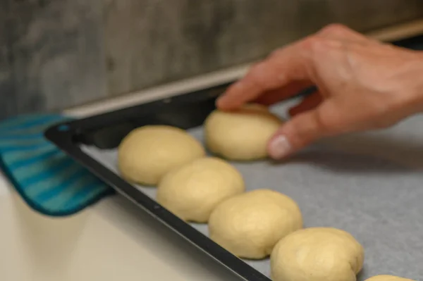 woman placing buns on a baking sheet 3
