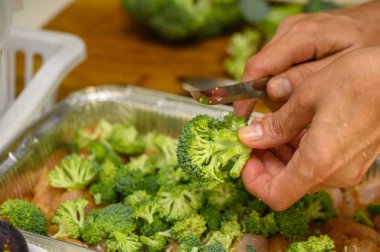 5 pişirmek için brokoliyi tavuk filetosuna kesen kadın.