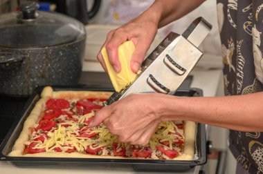 Kadın pizzayı peynirli, domatesli, tavuklu, peynirli hazırlıyor.