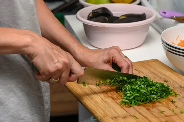 woman cutting parsley on a cutting board in the kitchen