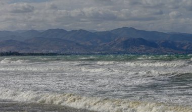 Akdeniz 'deki dalgaların manzarası ve sonbaharda Kıbrıs adasındaki dağlar