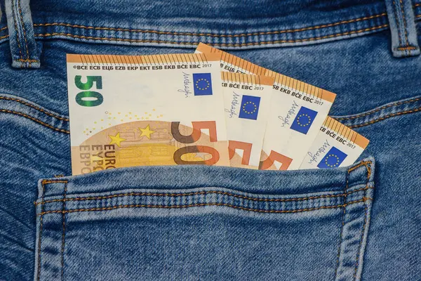 Stack of denim jeans with euro notes in pocket 2