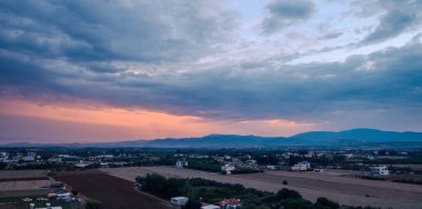 Cumulonimbus bulutlarıyla dramatik gökyüzü ve gün batımında güneşten gelen ışık.