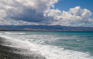 Deniz, bulutlar, dağlar ve dalgalar Akdeniz kıyısında güneşli bir günde Kıbrıs adasında,