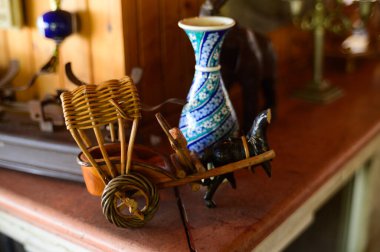 A unique wooden cart carries a colorful vase in a charming artisan shop full of treasures. clipart