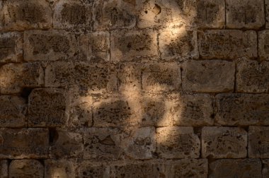 Gentle sunlight spills across an old stone wall, casting intriguing shapes that evoke a sense of history and beauty. clipart