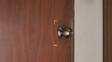 Kapıyı açan bir elin yakın çekimi. Tahta kapıyı açmak için kolu çeviren elin yakın çekimi..