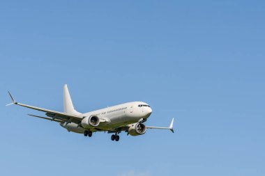 Havaalanına inmeden hemen önce mavi gökyüzüne karşı beyaz yolcu uçağı.