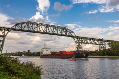 Almanya 'nın kuzeyinde Schleswig-Holstein eyâletinde, Kiel Kanalı' ndaki Hochdonn demiryolu köprüsünün altından geçen kargo gemisi. Kiel Kanalı dünyanın en sık kullanılan yapay su yollarından biridir..