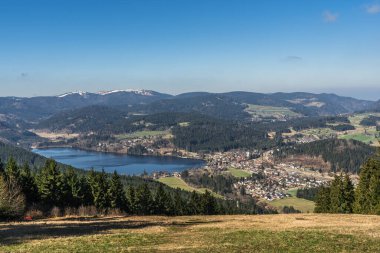 Titisee Gölü manzarası ve Hochfirst 'den aynı isimli spa kasabası, arka planda hafif karla kaplı Feldberg, Baden-Wuerttemberg, Almanya
