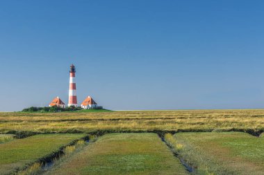 Westerheversand deniz fenerine, Westerhever 'e, Eiderstedt' e, Kuzey Frizya 'ya, Schleswig-Holstein, Almanya' nın kuzeyinde tuzlu bataklık ve gelgit derelerinin manzarası