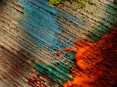 Turuncu, mavi ve yeşil renkler, ahşap bir yüzeye boyanmış.