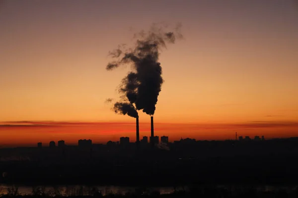 日落时的城市景观 乌克兰基辅市的红色日落 在城市景观的背景下吸烟的烟囱 火力发电厂在冬季寒冷季节的运行 — 图库照片