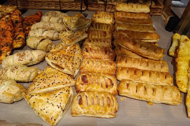 Mağazanın tezgahında yemek pişirmek. Farklı türde puf böreği. Farklı dolgulu taze puf börekleri ve otlu ve jambonlu haçlılar. Mobil fotoğrafçılık