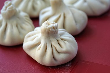 Plastik mutfak tahtasında ev yapımı khinkali. Çiğ Gürcü khinkalisi ve kuzu eti. Etle doldurulmuş çiğ khinkali. Hamur ve et ürünü. Donmuş, yarı bitmiş.