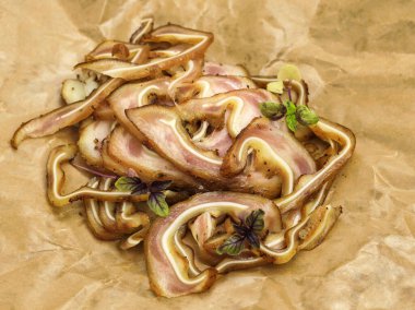 Mikro yeşil bazilikayla süslenmiş soslu kızarmış domuz parçaları. Kağıt üzerinde marine edilmiş domuz kulağı. Biraya atıştırmalık: domuz yağı, füme domuz kulağı.