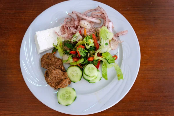 Cucumber salad with onion, cabbage, feta cheese and falafel in white plate on the table. Mediterranean Fresh Salad Arabic Salad with fresh ingredients Fresh Vegetables and spices. Traditional turkish