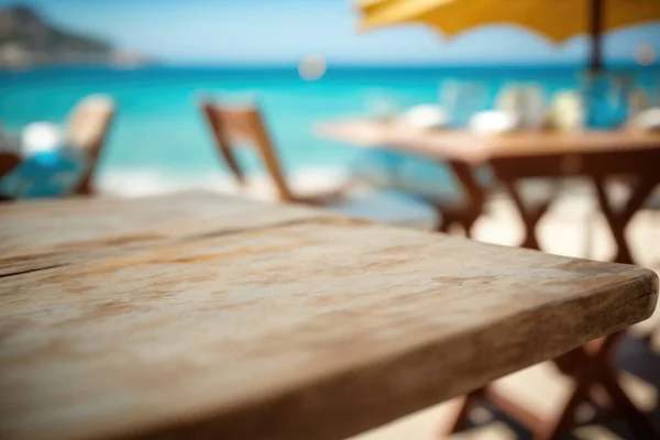 A table with a yellow umbrella over it on a beach side restaurant patio with a view of the ocean shallow depth of field a tilt shift photo photorealism