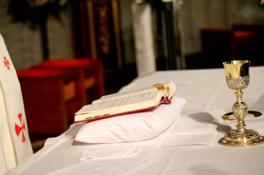 Kilisedeki masanın üstünde kutsal kitap ve altın kupa. 