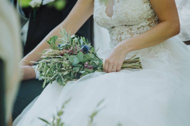 Gelin elinde bir buket çiçek tutuyor.