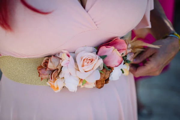 floral decoration on belt of lady in pink dress