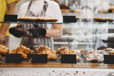 Interior details at the bakery and coffee shop. Bistro showcase with shelves of freshly croissants and bread in assortment. Zero waste shop or sustainable local small businesses at food service.
