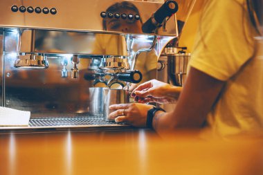 Professional coffee brewing in coffee shop. Close-up photo of espresso pouring from coffee machine. Barista make coffee cup in warm cozy atmosphere in small cafe.