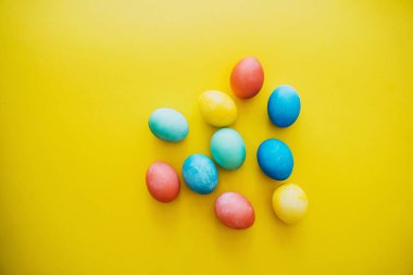 Colorful Easter eggs in basket on yellow background. Family with kids preparing for Easter at home. Top view, flat lay.