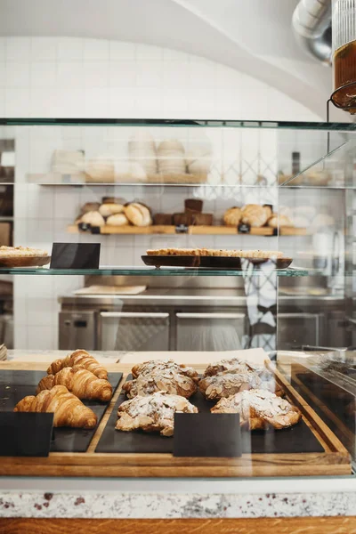 Interior details at the bakery and coffee shop. Bistro showcase with shelves of freshly croissants and bread in assortment. Zero waste shop or sustainable local small businesses at food service.