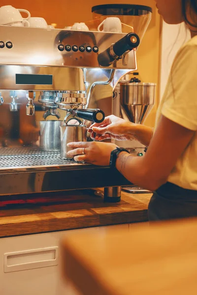 Professional coffee brewing in coffee shop. Close-up photo of espresso pouring from coffee machine. Barista make coffee cup in warm cozy atmosphere in small cafe.